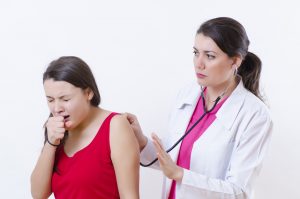 Doctor listening to patient's lungs while she coughs
