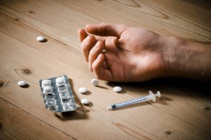 Drug user with pills and syringe