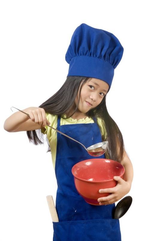 Kids Corner/Girl in Chef Outfit Holding Spoon above Bowl Photo